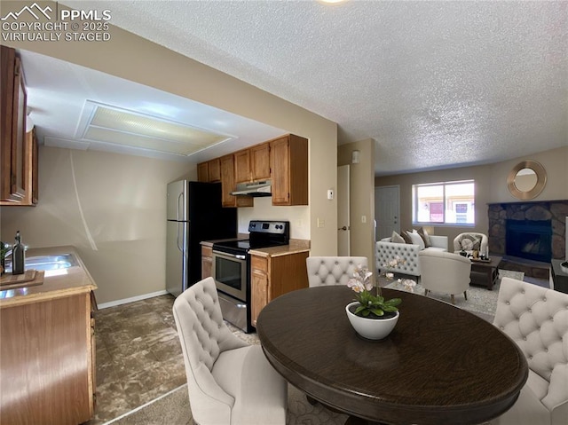 dining space with a stone fireplace, sink, and a textured ceiling