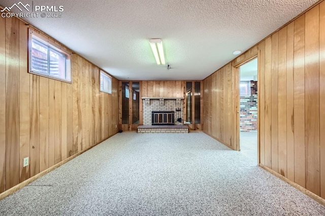 unfurnished living room featuring light carpet, a textured ceiling, a fireplace, and wood walls