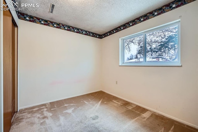 carpeted spare room featuring a textured ceiling