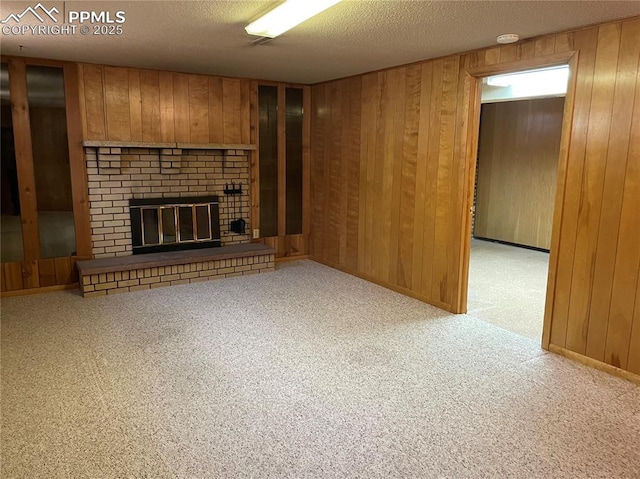 unfurnished living room with carpet floors, wooden walls, a textured ceiling, and a fireplace