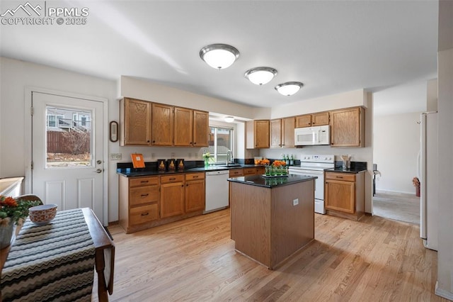 kitchen featuring sink, white appliances, light hardwood / wood-style floors, and a center island