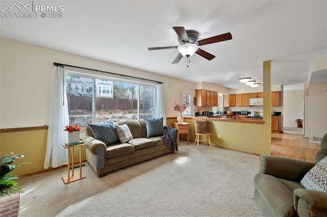 carpeted living room with ceiling fan and sink