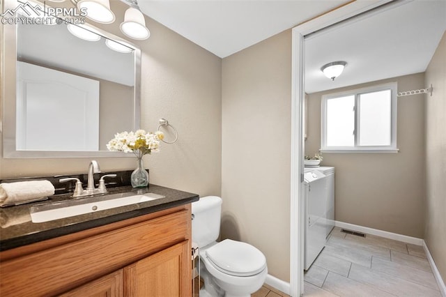 bathroom with vanity, washing machine and clothes dryer, tile patterned floors, and toilet