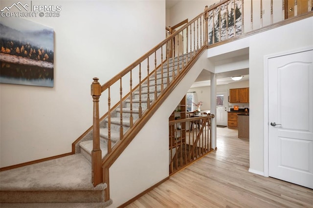 stairway featuring wood-type flooring and a towering ceiling