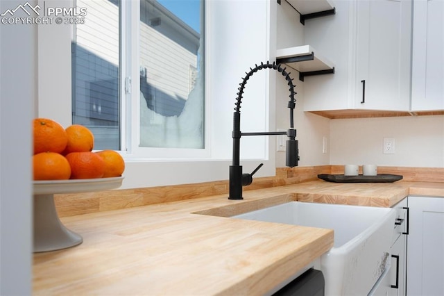 interior space featuring butcher block countertops, white cabinetry, and sink