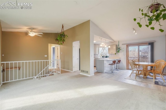 living room featuring light colored carpet, vaulted ceiling, ceiling fan, and sink