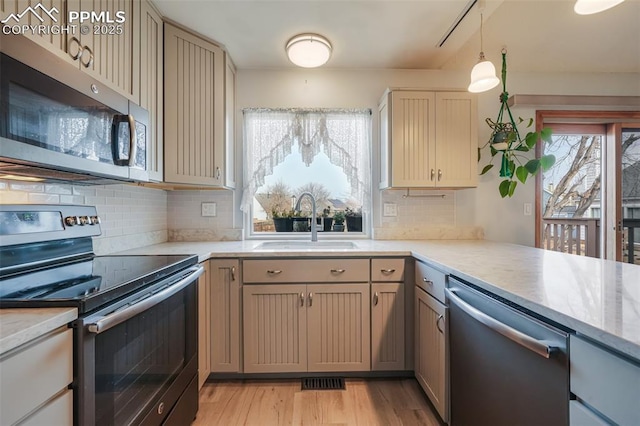 kitchen featuring appliances with stainless steel finishes, plenty of natural light, hanging light fixtures, and sink