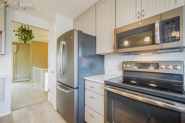 kitchen with appliances with stainless steel finishes, light wood-type flooring, and backsplash