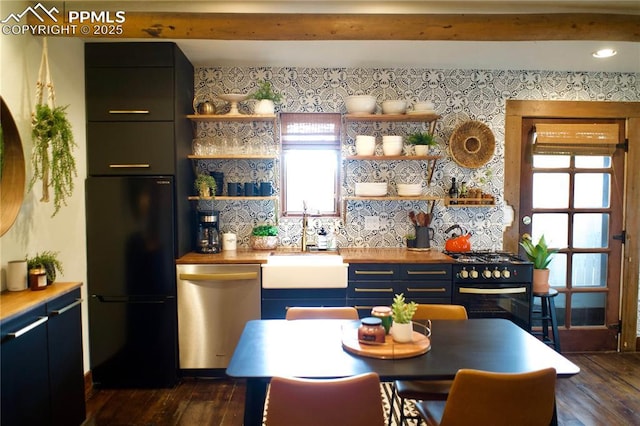 kitchen with dark wood-type flooring, black refrigerator, sink, gas range, and stainless steel dishwasher