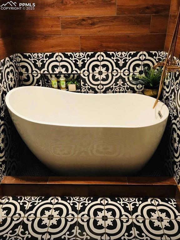 bathroom with tile patterned floors, a tub, and wood walls