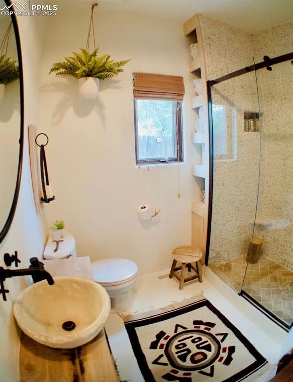 bathroom featuring toilet and a tile shower