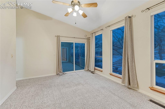 empty room featuring ceiling fan, vaulted ceiling, and carpet