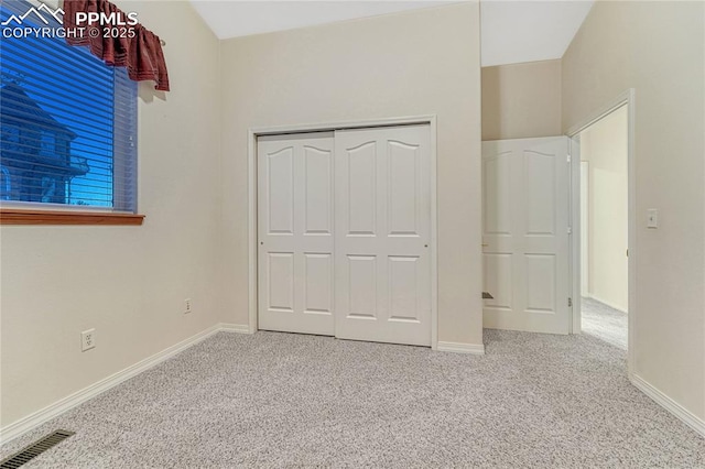 unfurnished bedroom featuring a closet and light carpet