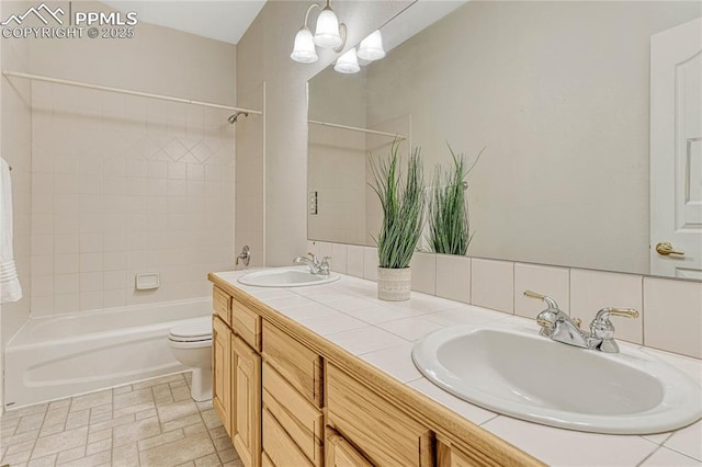 full bathroom with tiled shower / bath combo, vanity, toilet, and tasteful backsplash