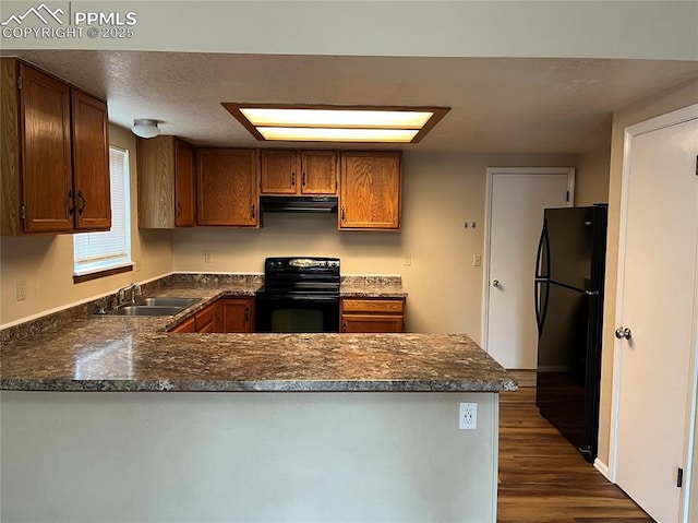 kitchen featuring exhaust hood, black appliances, sink, dark stone countertops, and kitchen peninsula