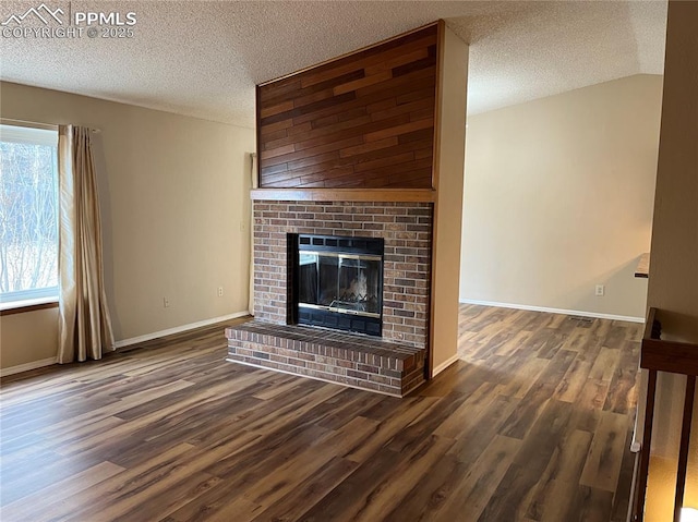 unfurnished living room with a textured ceiling, lofted ceiling, dark wood-type flooring, and a brick fireplace