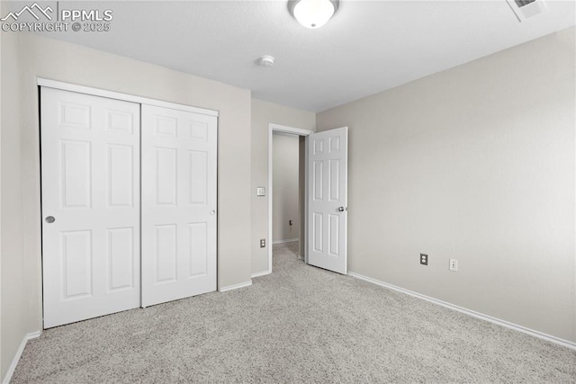 unfurnished bedroom featuring light colored carpet and a closet