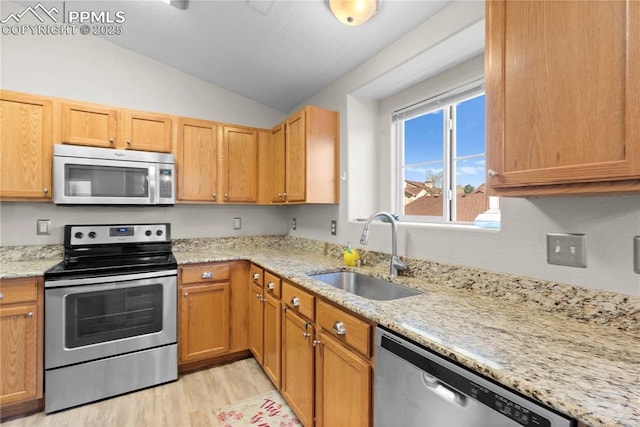 kitchen with light wood-type flooring, light stone counters, stainless steel appliances, sink, and lofted ceiling