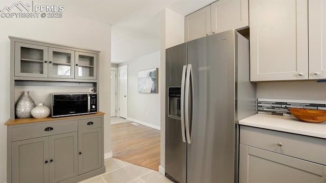 kitchen with stainless steel fridge with ice dispenser, light tile patterned floors, and gray cabinetry