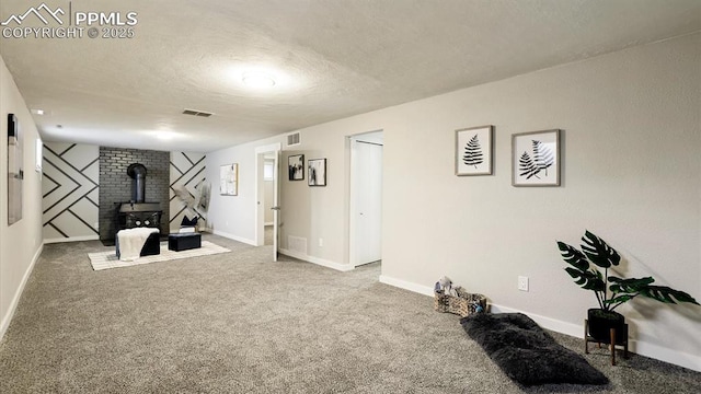 exercise area with a wood stove, carpet, and a textured ceiling