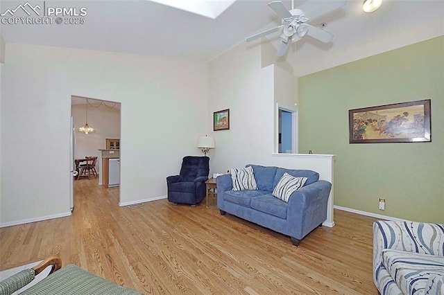 living room featuring ceiling fan with notable chandelier, light hardwood / wood-style flooring, and lofted ceiling