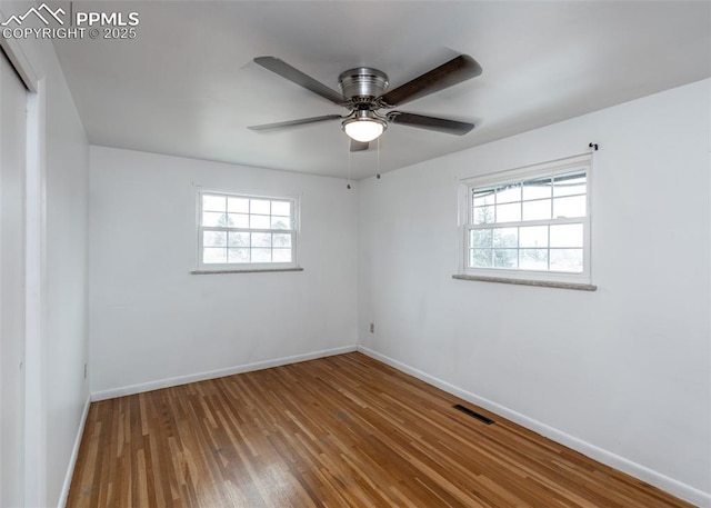 spare room featuring a healthy amount of sunlight, ceiling fan, and wood-type flooring