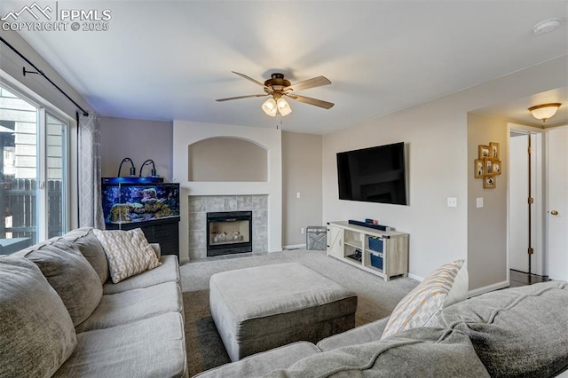 carpeted living room with a tile fireplace and ceiling fan