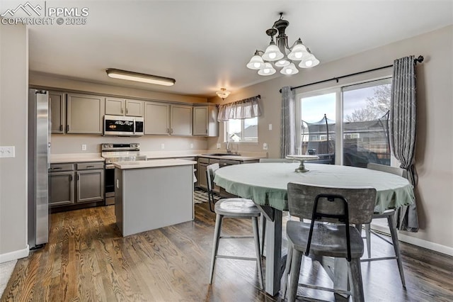 kitchen with sink, a center island, dark hardwood / wood-style floors, pendant lighting, and appliances with stainless steel finishes