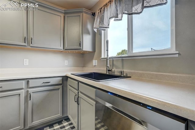 kitchen with stainless steel dishwasher, gray cabinetry, and sink