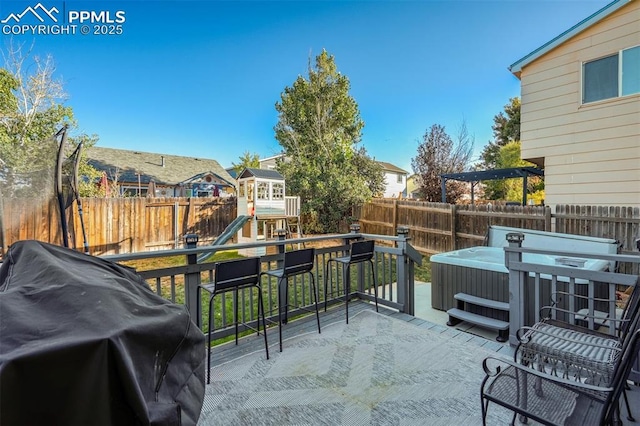 view of patio with a playground, area for grilling, a hot tub, and a deck