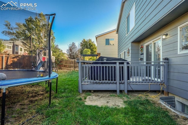 view of yard featuring a trampoline and a wooden deck