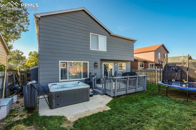 rear view of property featuring a wooden deck, central AC, a trampoline, a hot tub, and a lawn