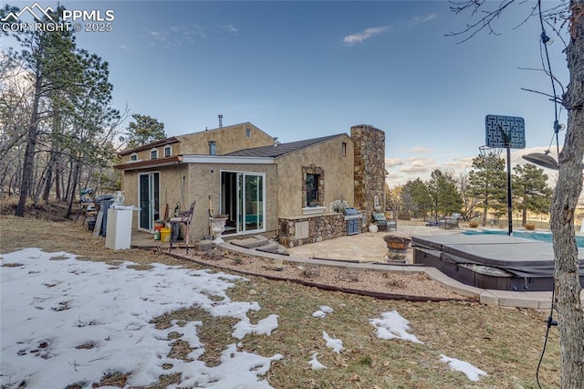 snow covered house featuring a patio area and exterior kitchen