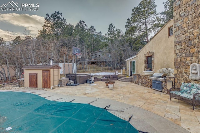 view of patio with an outdoor kitchen, a swimming pool with hot tub, and grilling area