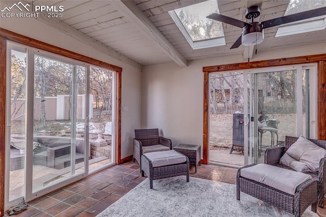 sunroom / solarium featuring ceiling fan, beam ceiling, wooden ceiling, and a skylight