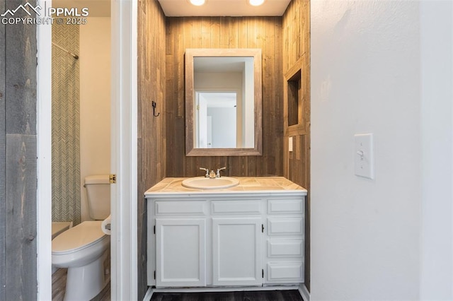 bathroom with vanity, toilet, and wooden walls