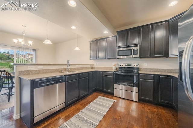 kitchen with stainless steel appliances, dark wood-type flooring, sink, an inviting chandelier, and hanging light fixtures