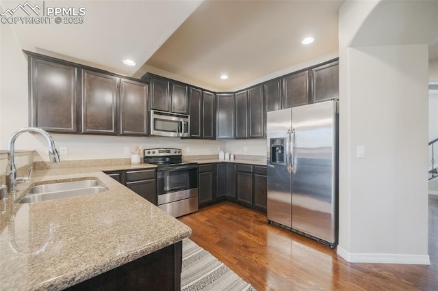 kitchen featuring light stone counters, sink, hardwood / wood-style floors, and appliances with stainless steel finishes