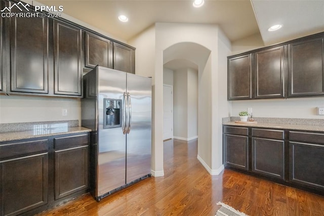 kitchen featuring dark brown cabinets, wood-type flooring, and stainless steel refrigerator with ice dispenser