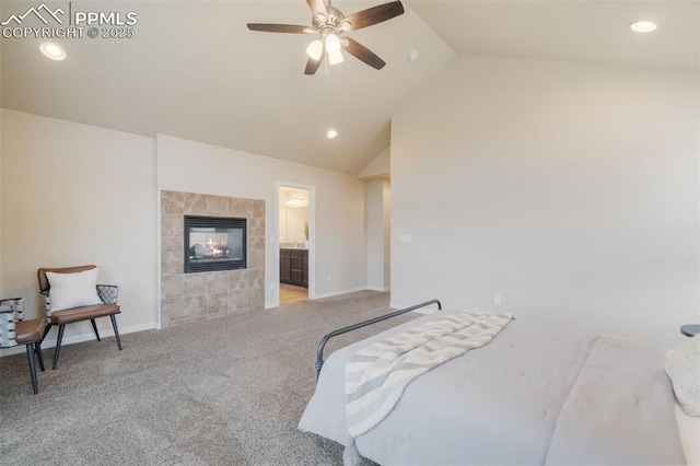 carpeted bedroom with connected bathroom, a tile fireplace, ceiling fan, and lofted ceiling