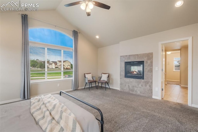 bedroom with a tiled fireplace, ceiling fan, light carpet, and lofted ceiling