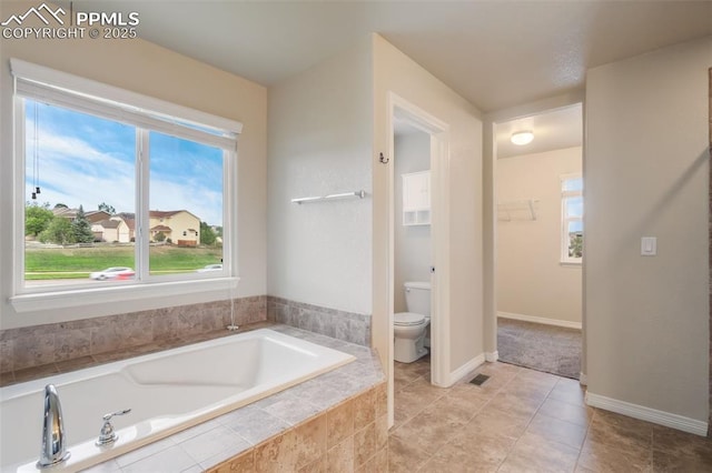 bathroom with a relaxing tiled tub and toilet