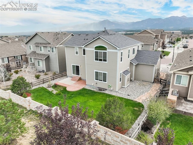 rear view of house with a mountain view, a yard, and a patio