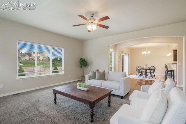 carpeted living room with ceiling fan with notable chandelier