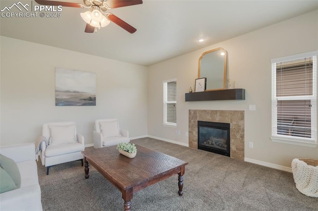 living room with ceiling fan, carpet floors, and a tiled fireplace