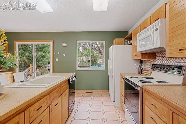 kitchen with a textured ceiling, white appliances, backsplash, and sink