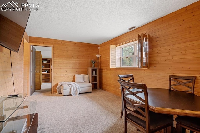 carpeted home office with wooden walls and a textured ceiling