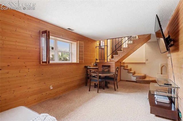 dining area featuring wood walls, carpet floors, and a textured ceiling