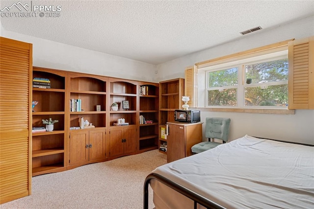 bedroom with light colored carpet and a textured ceiling