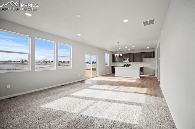 unfurnished living room featuring a notable chandelier and light colored carpet